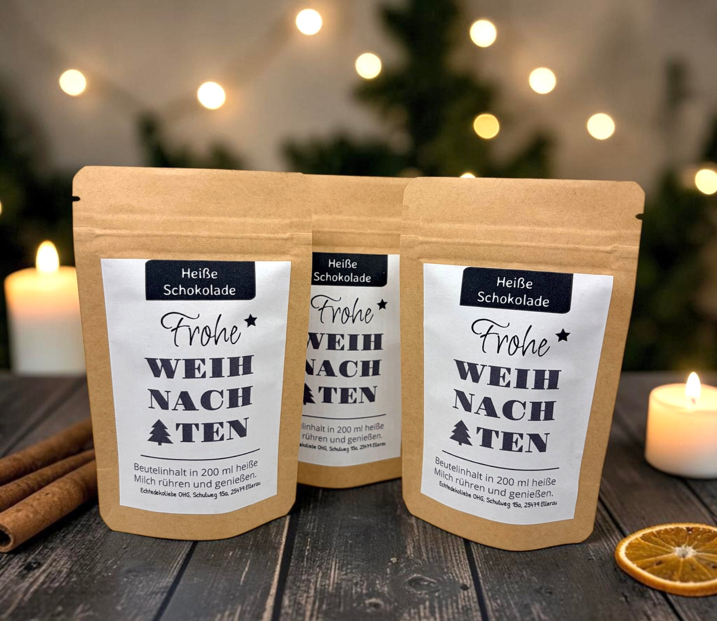 Braune Kraftpapiertüten mit weihnachtlichem Design stehen dekorativ auf einem rustikalen Holztisch. Die Tüten sind mit einem winterlich gestalteten Etikett versehen und enthalten eine Getränkemischung bzw. ein Heißgetränk zum Genießen. Im Hintergrund sorgen Tannenzweige, warme Lichter und weihnachtliche Dekoration für eine gemütliche Adventsstimmung.