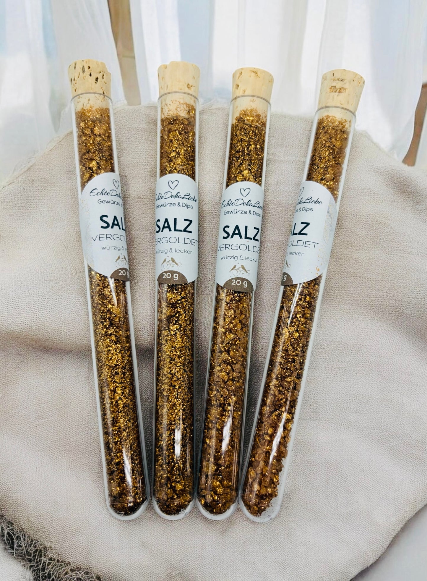 Sieben Reagenzgläser mit Naturkorken, gefüllt mit verschiedenen Gewürzen und Salzen. Zu sehen sind Rühreigewürz, Kräutersalz, Himalayasalz, Pommesgewürz, Aglio-Olio-Gewürz, vergoldeter Pfeffer und vergoldetes Salz. Die Gläser tragen moderne weiße Etiketten mit Produktname und Füllmenge. Arrangiert auf hellem Holzhintergrund mit dekorativen Trockenblumen – eine besondere Geschenkidee für Gewürzliebhaber.