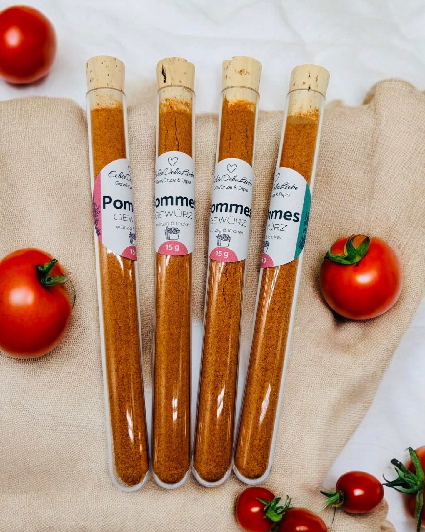 Sieben Reagenzgläser mit Naturkorken, gefüllt mit verschiedenen Gewürzen und Salzen. Zu sehen sind Rühreigewürz, Kräutersalz, Himalayasalz, Pommesgewürz, Aglio-Olio-Gewürz, vergoldeter Pfeffer und vergoldetes Salz. Die Gläser tragen moderne weiße Etiketten mit Produktname und Füllmenge. Arrangiert auf hellem Holzhintergrund mit dekorativen Trockenblumen – eine besondere Geschenkidee für Gewürzliebhaber.