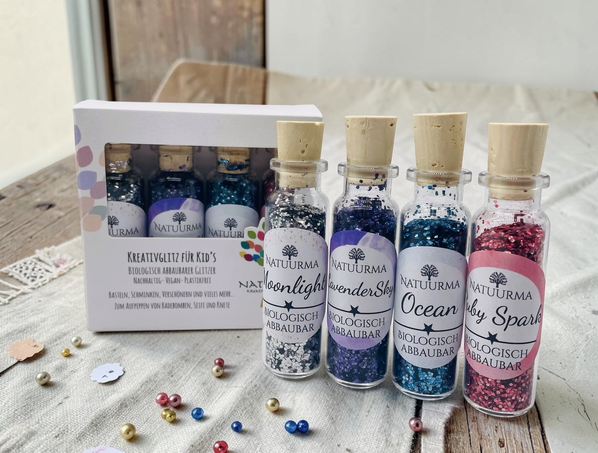 Das Bild zeigt unser hochwertiges KreativGlitzer-Set mit vier Glasfläschchen aus Glas und Naturkorken. Enthalten sind die Farben Silber, Blau, Lila und Rot. Der biologisch abbaubare Glitzer ist plastikfrei, vegan und Made in Germany. Ideal für Bastelarbeiten, DIY-Projekte, Sensorik, Matschküchen, Dekorationen, Grußkarten, Geschenkverpackungen und viele weitere kreative Ideen. Liebevoll verpackt von Echte DekoLiebe.
