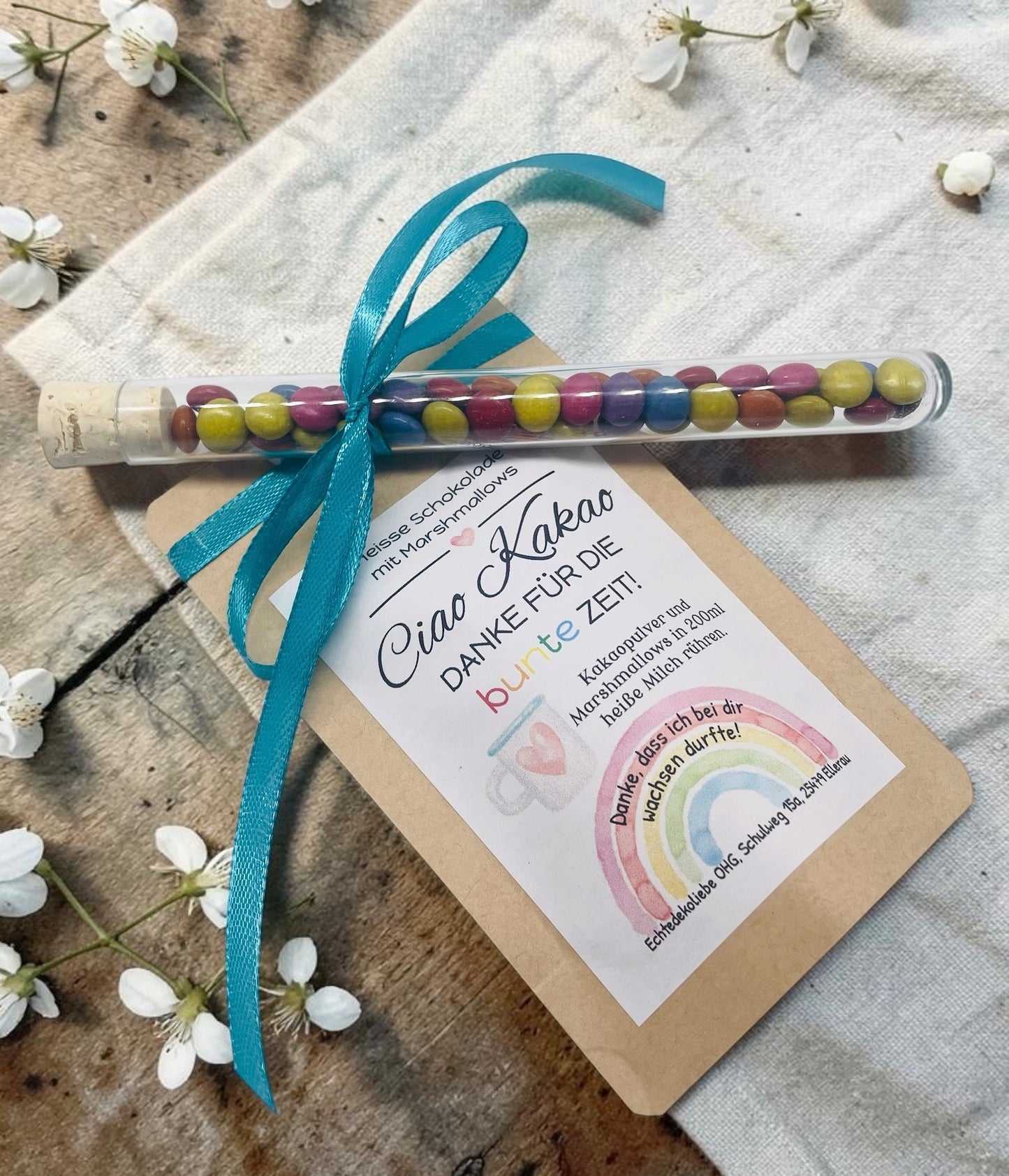 Liebevoll gestaltetes Abschiedsgeschenk mit heißer Schokolade und Marshmallows im Kraftpapierbeutel. Das Etikett „Ciao Kakao – Danke für die bunte Zeit!“ wird durch einen farbenfrohen Regenbogen mit dem Spruch „Danke, dass du mich hast wachsen lassen.“ ergänzt. Perfekt als kleines Dankeschön für Erzieherinnen, Lehrer oder Tagesmütter. Optional mit Reagenzglas voller bunter Schokolinsen als süße Aufmerksamkeit.