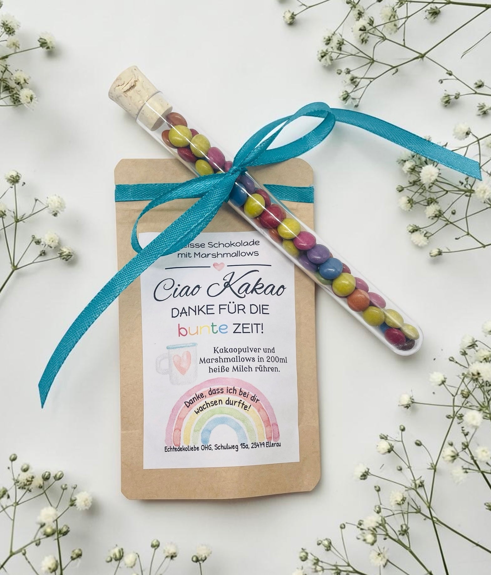 Liebevoll gestaltetes Abschiedsgeschenk mit heißer Schokolade und Marshmallows im Kraftpapierbeutel. Das Etikett „Ciao Kakao – Danke für die bunte Zeit!“ wird durch einen farbenfrohen Regenbogen mit dem Spruch „Danke, dass du mich hast wachsen lassen.“ ergänzt. Perfekt als kleines Dankeschön für Erzieherinnen, Lehrer oder Tagesmütter. Optional mit Reagenzglas voller bunter Schokolinsen als süße Aufmerksamkeit.