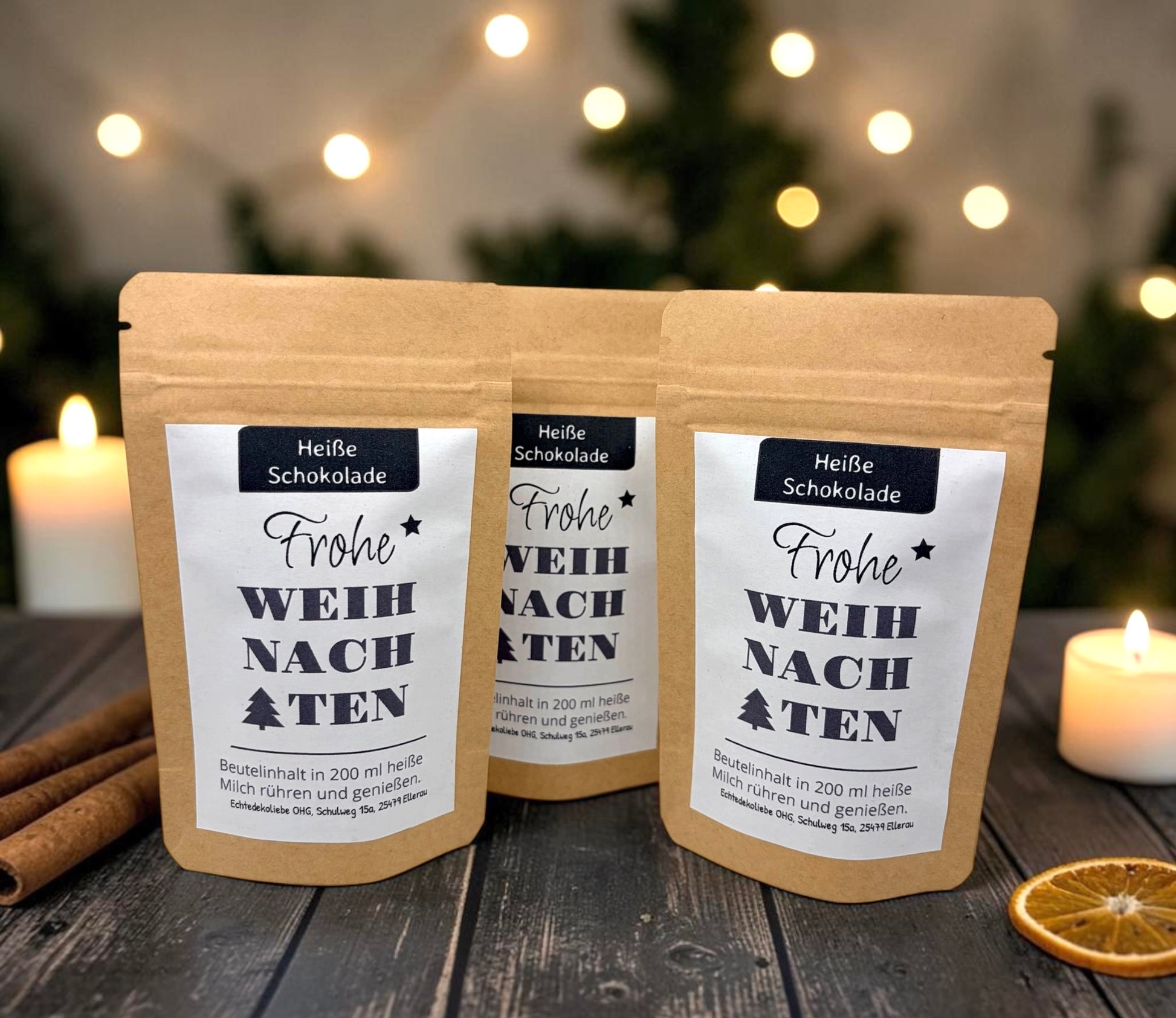 Braune Kraftpapiertüten mit weihnachtlichem Design stehen dekorativ auf einem rustikalen Holztisch. Die Tüten sind mit einem winterlich gestalteten Etikett versehen und enthalten eine Getränkemischung bzw. ein Heißgetränk zum Genießen. Im Hintergrund sorgen Tannenzweige, warme Lichter und weihnachtliche Dekoration für eine gemütliche Adventsstimmung.