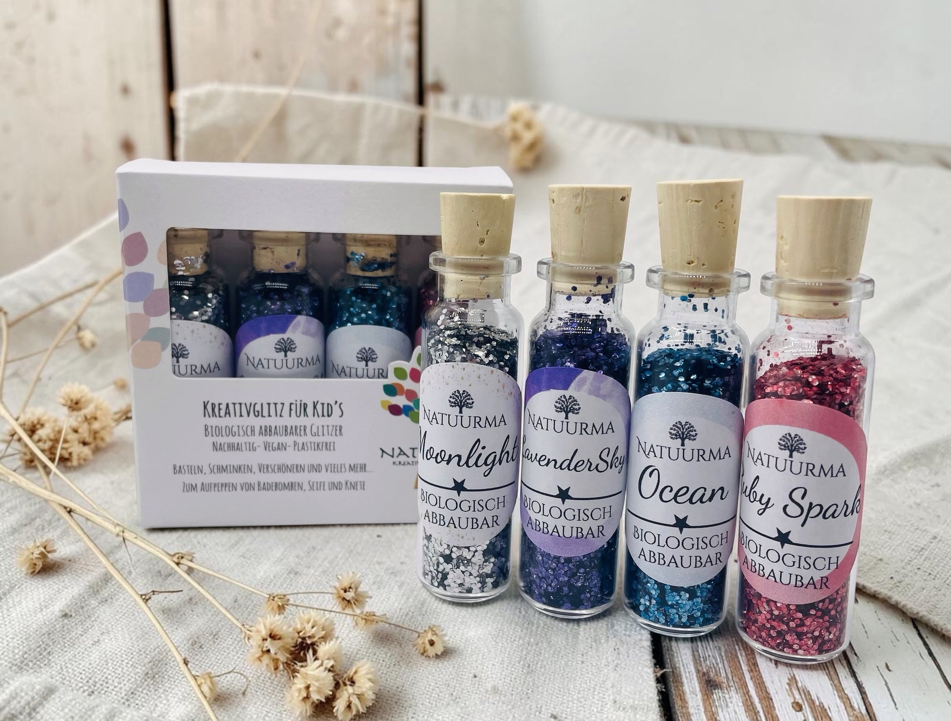 Das Bild zeigt unser hochwertiges KreativGlitzer-Set mit vier Glasfläschchen aus Glas und Naturkorken. Enthalten sind die Farben Silber, Blau, Lila und Rot. Der biologisch abbaubare Glitzer ist plastikfrei, vegan und Made in Germany. Ideal für Bastelarbeiten, DIY-Projekte, Sensorik, Matschküchen, Dekorationen, Grußkarten, Geschenkverpackungen und viele weitere kreative Ideen. Liebevoll verpackt von Echte DekoLiebe.